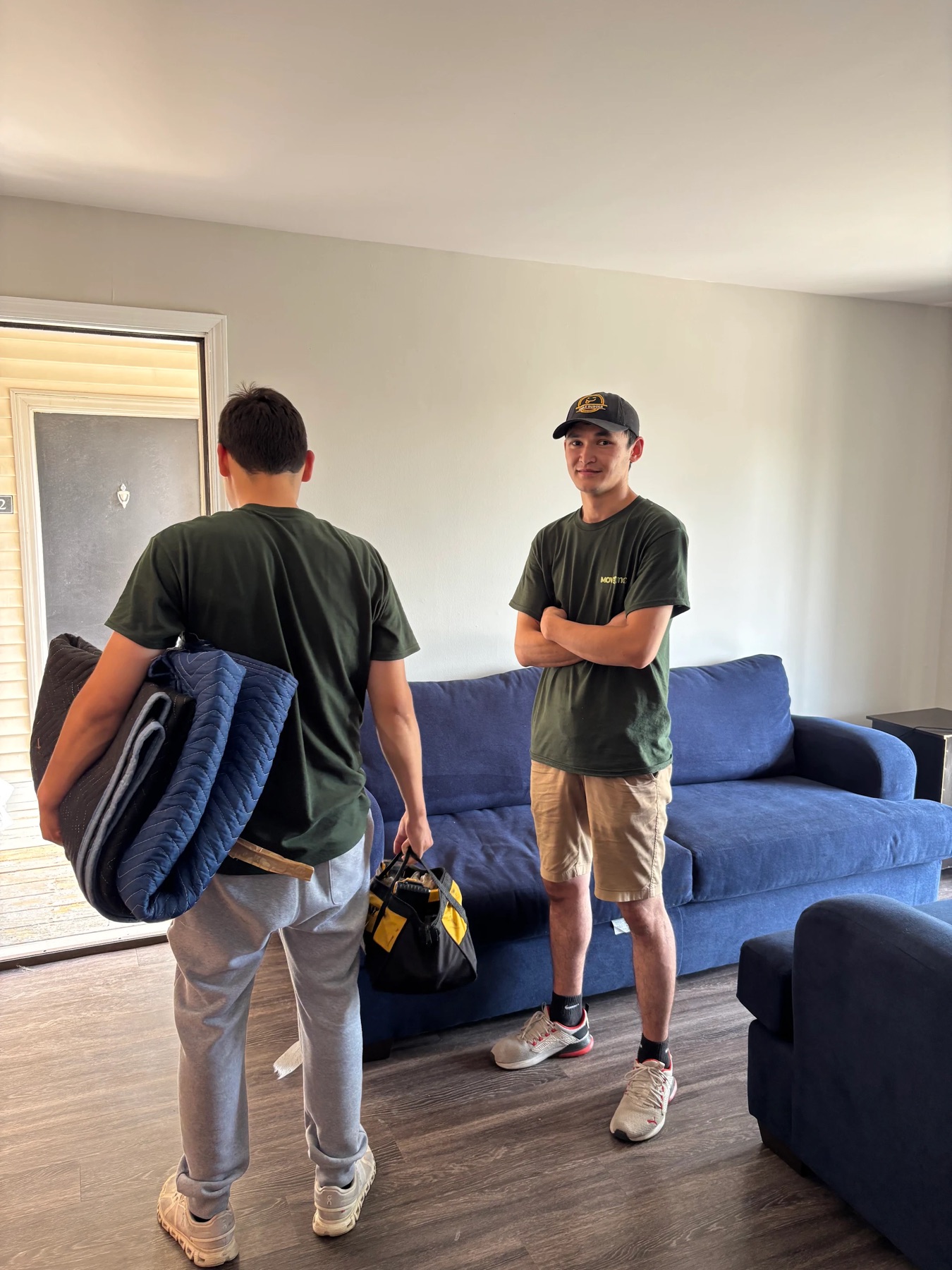 Two MoveMax movers with moving blankets and a tool bag