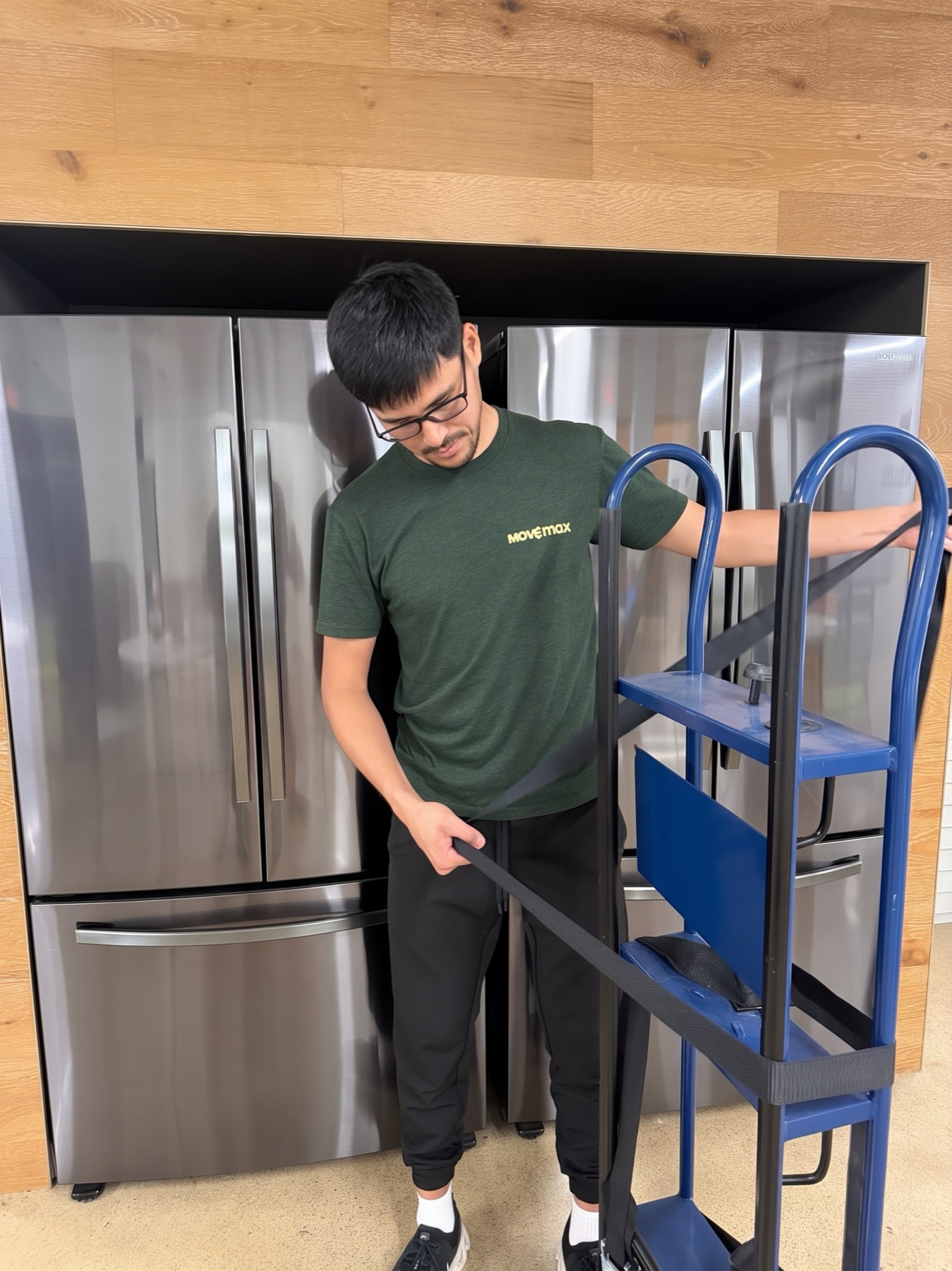 A MoveMax mover strapping a refrigerator to a dolly